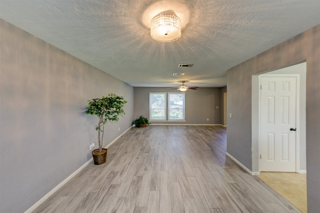 empty room featuring light hardwood / wood-style flooring, ceiling fan, and a textured ceiling