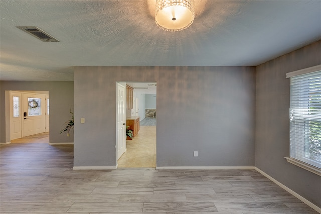 unfurnished room featuring a textured ceiling