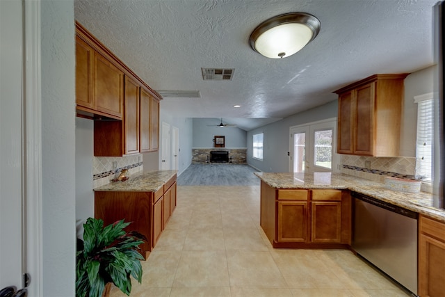 kitchen featuring kitchen peninsula, stainless steel dishwasher, ceiling fan, light tile patterned floors, and a fireplace