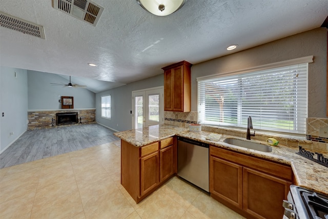 kitchen with kitchen peninsula, stainless steel appliances, vaulted ceiling, sink, and a fireplace