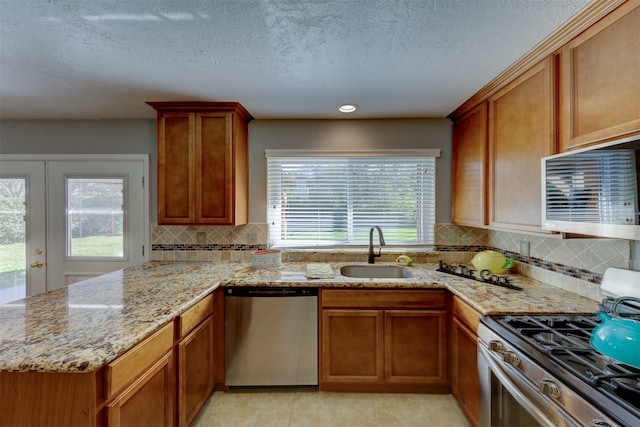 kitchen with sink, appliances with stainless steel finishes, french doors, backsplash, and light stone countertops