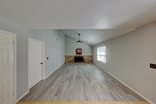 unfurnished living room featuring light hardwood / wood-style flooring, ceiling fan, lofted ceiling, and a textured ceiling