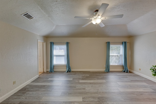 spare room featuring light hardwood / wood-style flooring, a wealth of natural light, and lofted ceiling