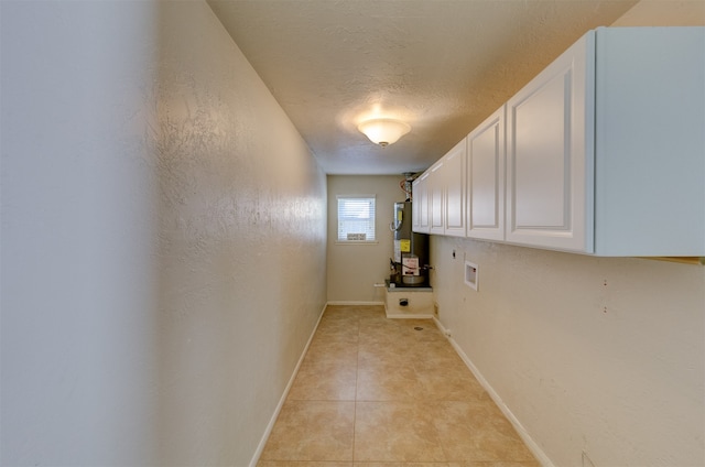 laundry room featuring cabinets, washer hookup, gas water heater, a textured ceiling, and light tile patterned floors