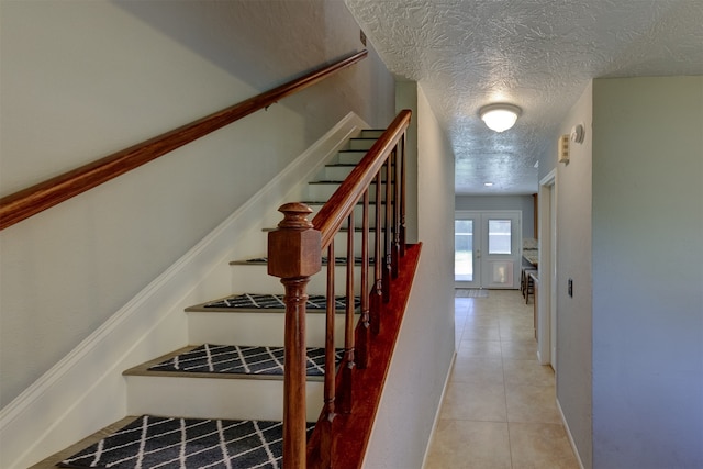 stairs with tile patterned flooring and a textured ceiling