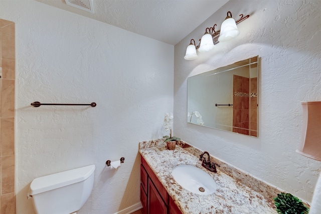 bathroom with vanity, a textured ceiling, and toilet