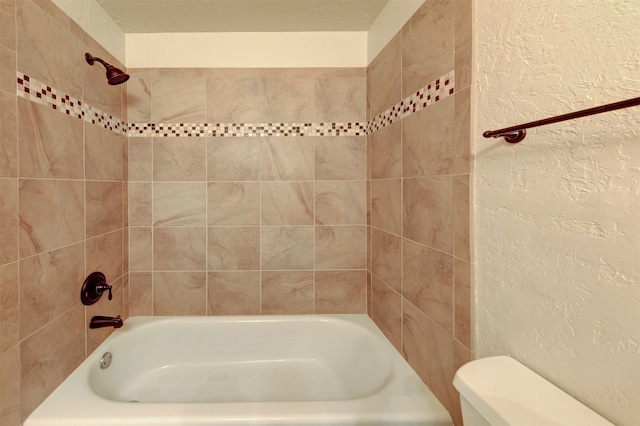 bathroom with toilet, tiled shower / bath combo, and a textured ceiling