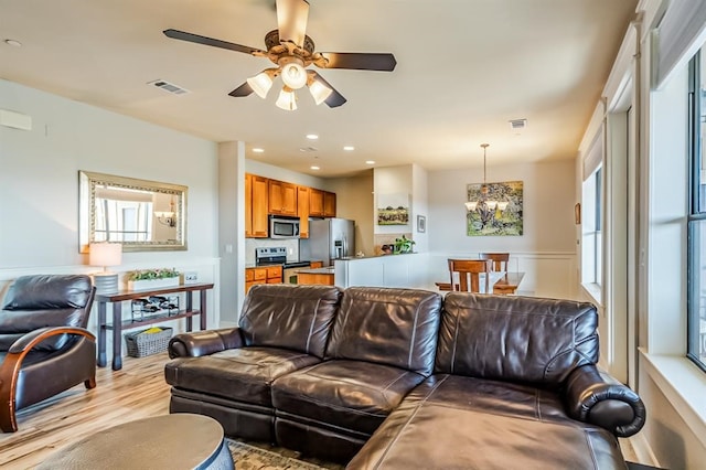 living room featuring light hardwood / wood-style flooring and ceiling fan with notable chandelier