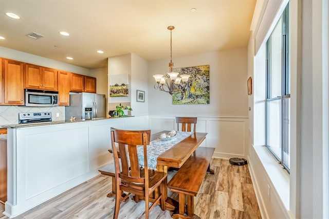 dining area featuring light hardwood / wood-style flooring and a notable chandelier