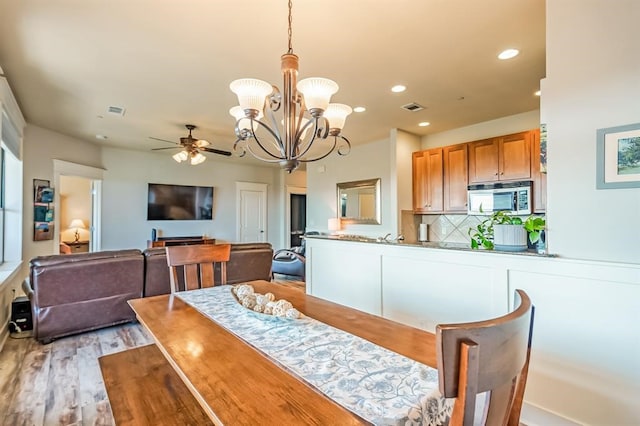 dining room with hardwood / wood-style floors and ceiling fan with notable chandelier