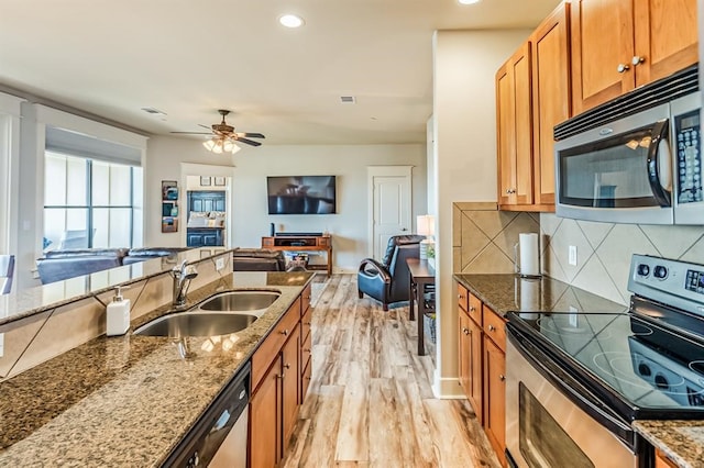 kitchen with stone counters, sink, light hardwood / wood-style floors, and appliances with stainless steel finishes