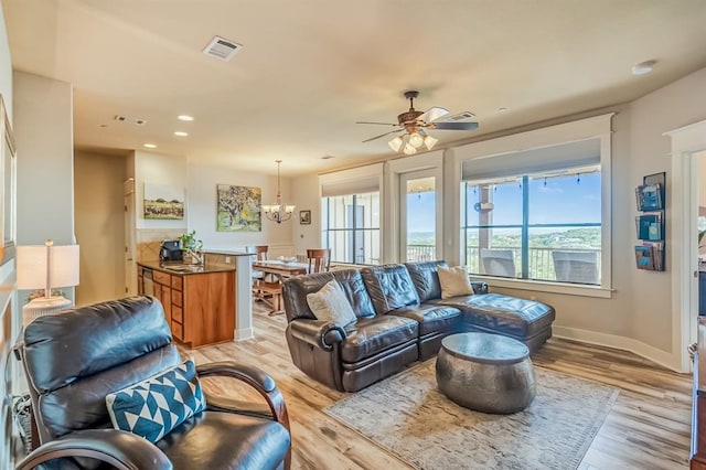 living room with ceiling fan with notable chandelier and light wood-type flooring