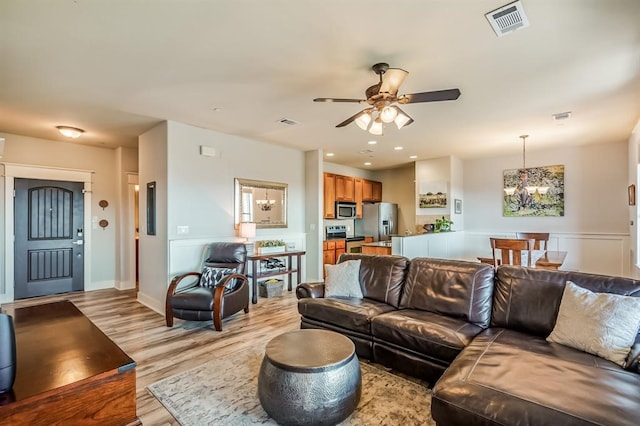 living room featuring light hardwood / wood-style floors and ceiling fan with notable chandelier