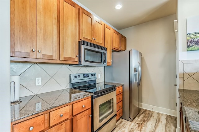 kitchen featuring stone counters, light wood-type flooring, stainless steel appliances, and tasteful backsplash