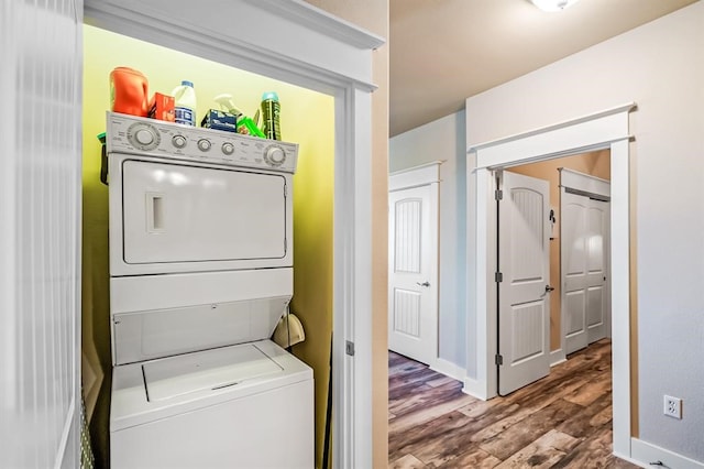 laundry room featuring stacked washer and dryer and hardwood / wood-style flooring