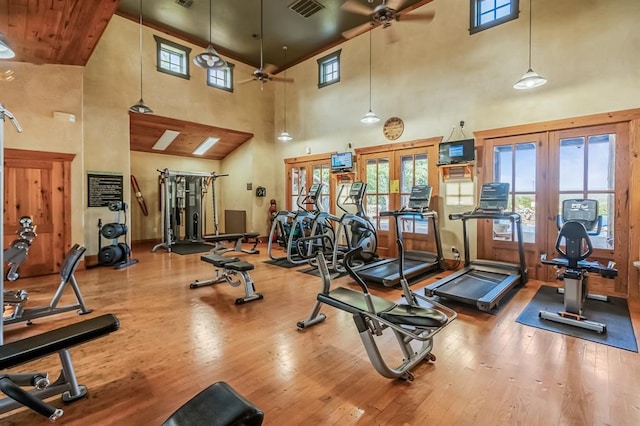 gym with ceiling fan, french doors, high vaulted ceiling, and hardwood / wood-style flooring