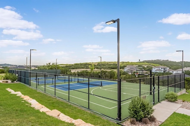 view of tennis court featuring a yard and basketball hoop