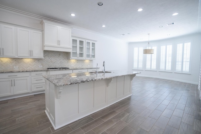 kitchen featuring sink, white cabinets, dark wood-type flooring, and a center island with sink