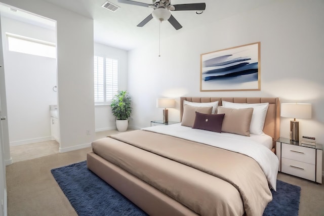 bedroom with light carpet, connected bathroom, and ceiling fan