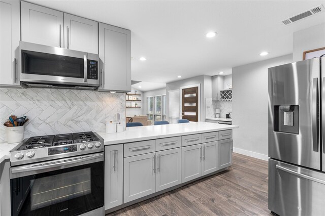 11207 Wood Lodge Dr, Houston, TX 77077 - kitchen with stainless steel appliances, a peninsula, gray cabinets, tasteful backsplash, and light countertops