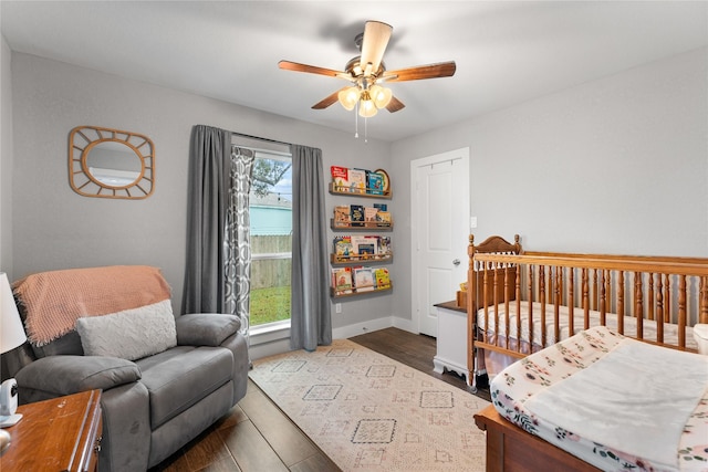 11207 Wood Lodge Dr, Houston, TX 77077 - bedroom with dark wood-type flooring, a nursery area, baseboards, and a ceiling fan