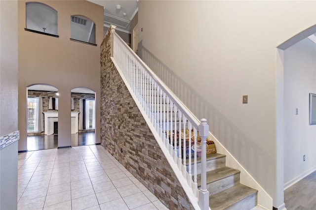 stairway with a fireplace, a towering ceiling, and tile patterned floors