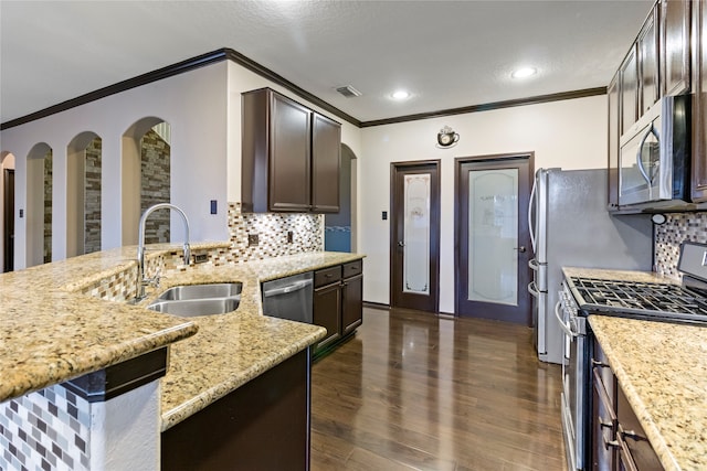 kitchen with sink, appliances with stainless steel finishes, light stone counters, and dark brown cabinetry