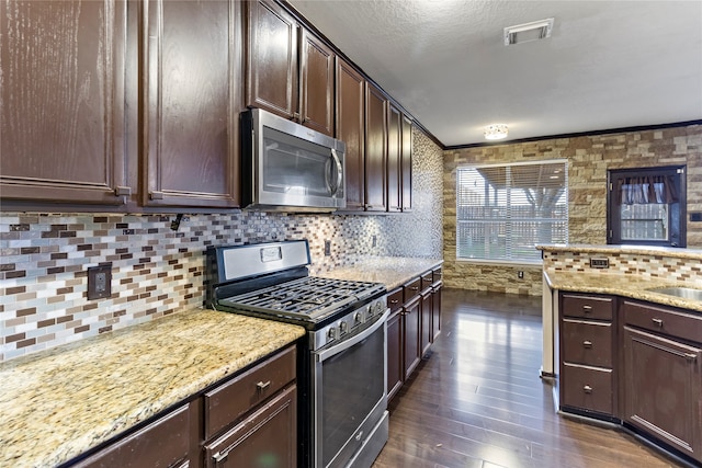 kitchen featuring ornamental molding, decorative backsplash, appliances with stainless steel finishes, dark brown cabinets, and dark hardwood / wood-style floors