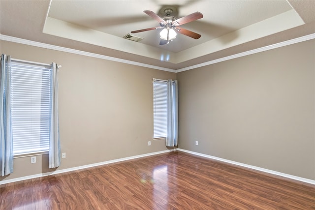 unfurnished room featuring a tray ceiling, crown molding, and dark wood-type flooring