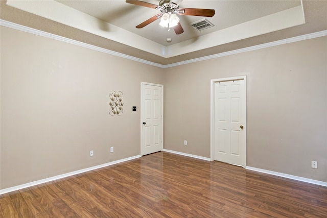 spare room featuring a raised ceiling, crown molding, ceiling fan, and dark wood-type flooring