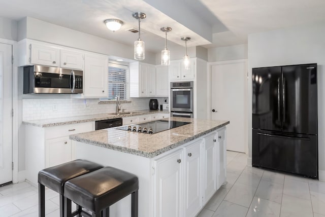 kitchen with white cabinets, a kitchen island, hanging light fixtures, black appliances, and light stone counters