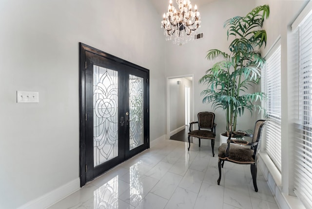 foyer with a towering ceiling, french doors, an inviting chandelier, and plenty of natural light