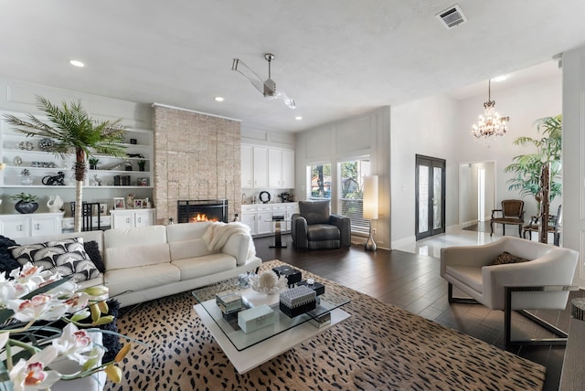 living room featuring a fireplace, ceiling fan with notable chandelier, and dark wood-type flooring