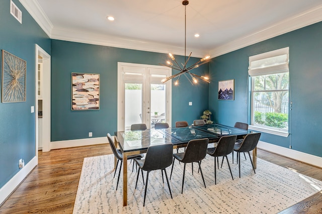 dining space with hardwood / wood-style flooring, a notable chandelier, and crown molding