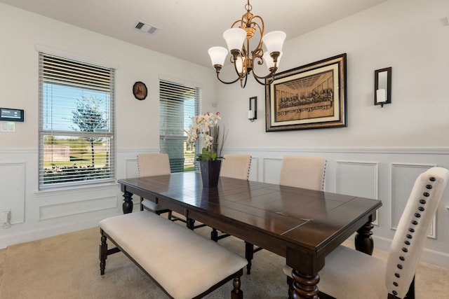 carpeted dining room featuring a notable chandelier