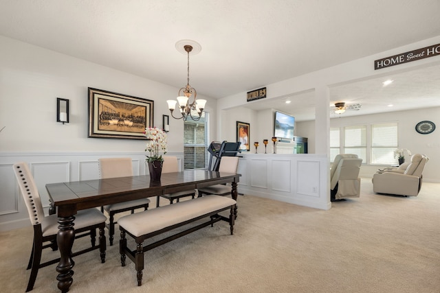 carpeted dining space with ceiling fan with notable chandelier