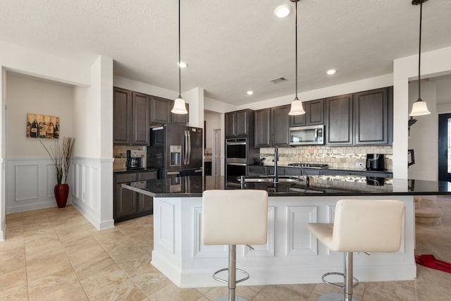 kitchen featuring a kitchen breakfast bar, backsplash, stainless steel appliances, sink, and pendant lighting