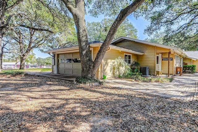 ranch-style home featuring central air condition unit and a garage