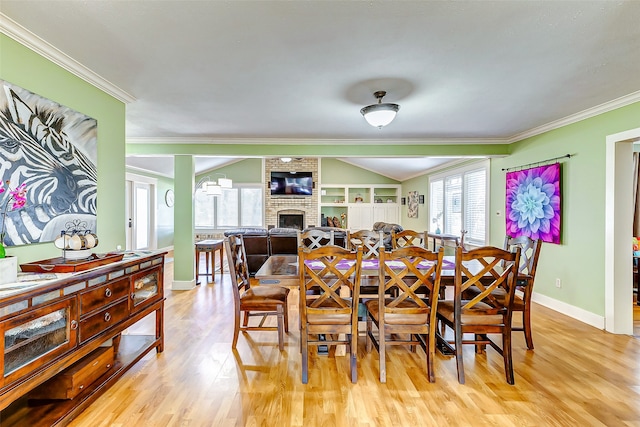 dining room with a fireplace, crown molding, and light wood-type flooring