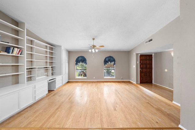 unfurnished living room featuring light hardwood / wood-style flooring, ceiling fan, built in desk, and lofted ceiling