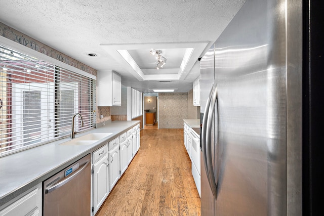 kitchen featuring light hardwood / wood-style flooring, white cabinetry, sink, a wealth of natural light, and appliances with stainless steel finishes