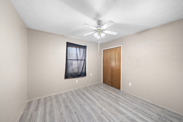 empty room featuring ceiling fan, a textured ceiling, and light wood-type flooring