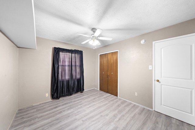 unfurnished bedroom with light hardwood / wood-style flooring, ceiling fan, a closet, and a textured ceiling