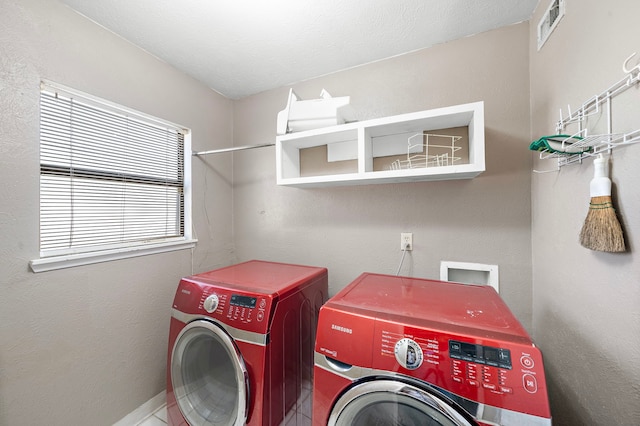 laundry area with a textured ceiling, separate washer and dryer, and a wealth of natural light