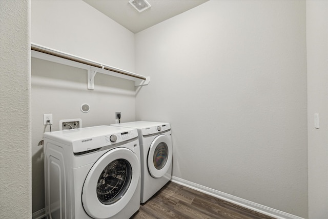 laundry area featuring washing machine and clothes dryer and dark hardwood / wood-style flooring