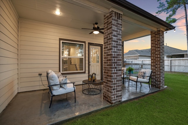 patio terrace at dusk featuring a lawn and ceiling fan