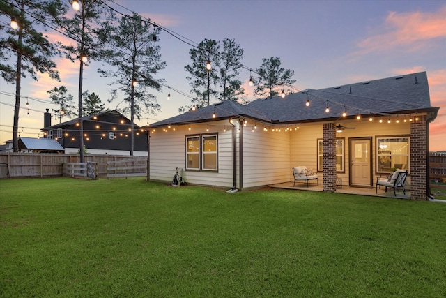 back house at dusk with a yard and a patio