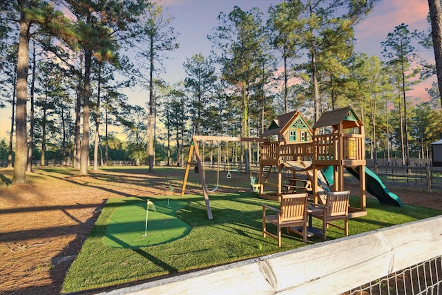 playground at dusk featuring a lawn