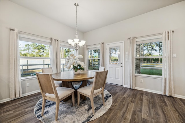 dining space featuring dark wood-type flooring, a healthy amount of sunlight, and an inviting chandelier