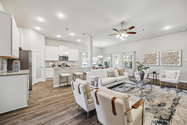 living room with dark hardwood / wood-style flooring and ceiling fan with notable chandelier